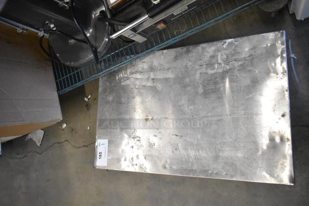 Metal dolly with commercial casters, showing signs of wear. Label visible with text "LOT 185, QTY 1."