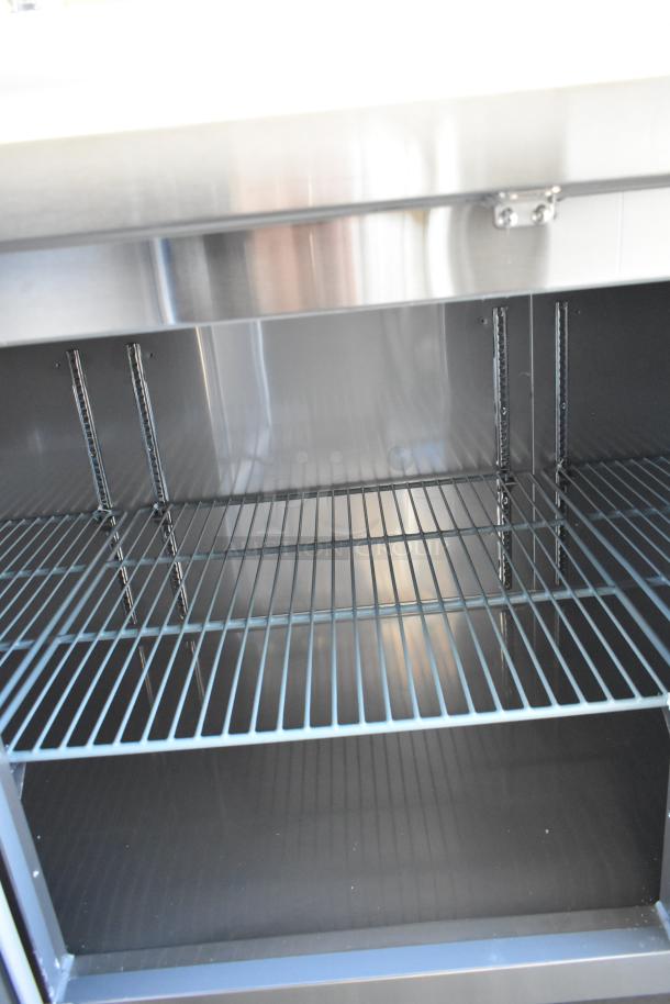 Brand new Avantco 178SSPPT3 stainless steel pizza prep table, commercial casters, 115V, 1 phase, interior shelf detail.