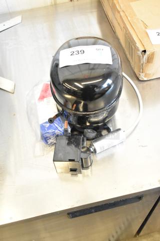 Brand new Cubigel NUT70NR compressor, 115V, 1 phase, with minor scratches and dents. Auction tag visible.