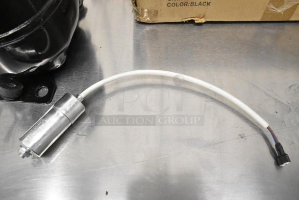 Brand new Cubigel NUT70NR Compressor, 115V, 1 Phase, minor scratches, includes electrical connector and mounting bracket.