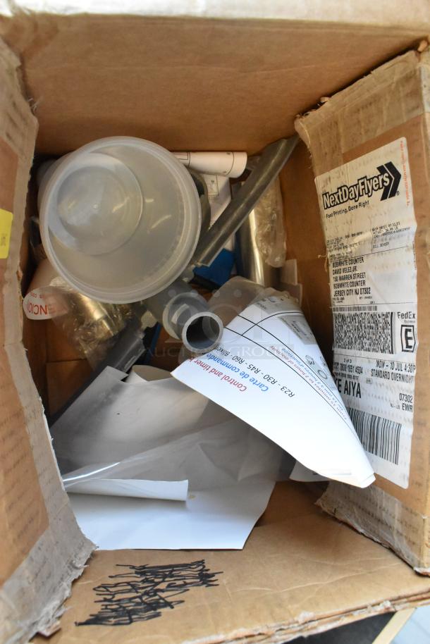 Box of assorted items including a plastic cup, tube, and various papers. Box labeled "NextDayFlyers." Mixed condition.
