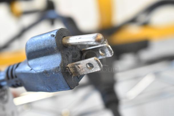 Close-up of a worn, three-prong electrical plug, part of an auction lot including a work light and Speedwell item.