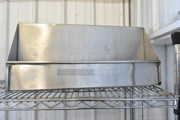 Stainless steel storage bin on a wire shelf, slightly worn with visible scratches, suitable for organizing tools or materials.