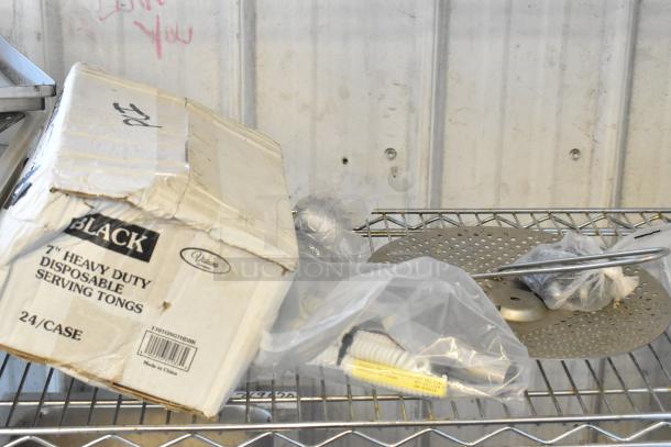 Tiered auction lot including dice, serving tongs, metal pieces, casters, and MyZone MZ-3 band. Box of tongs is visible.