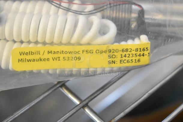 Assorted auction lot with dice, serving tongs, metal parts, commercial casters, MyZone MZ-3 Band. Yellow label reads Welbilt/Manitowoc info.