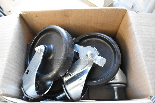 Cardboard box containing commercial metal casters with black wheels, some assembly required.