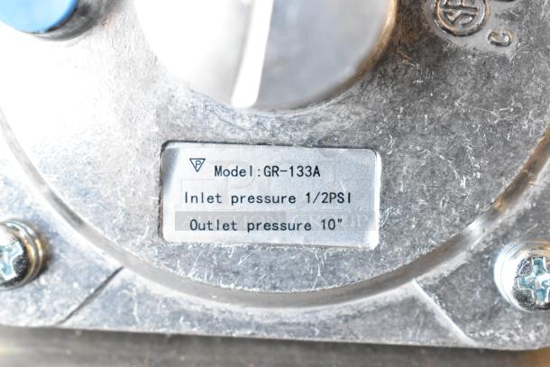 GR-133A gas connector label showing model, inlet pressure 1/2 PSI, outlet pressure 10 inches, metallic surface.