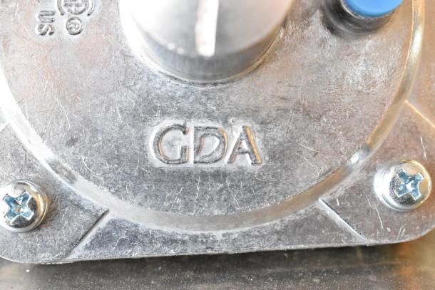 Close-up of metal surface with "GDA" marking, part of 3-item auction including a dough hook, Fisher 10863 jet spray, and gas connector.