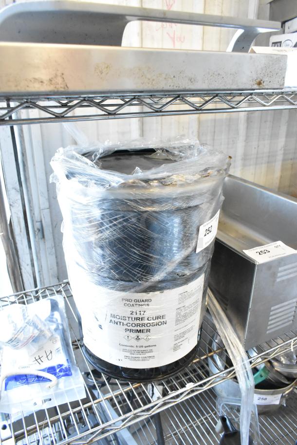 Pro Guard 2117 Moisture Cure Anti Corrosion Primer, 5-gallon container, sealed and labeled, on a metal shelf.