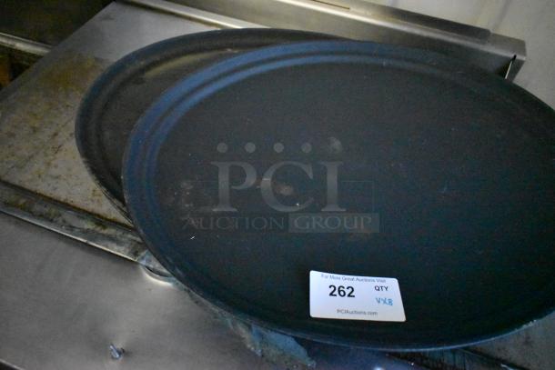 Eight items including black serving trays and a metal pizza peel, marked with auction tag "262, QTY VX8."