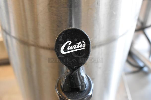 Curtis stainless steel beverage holder dispenser with branded spout, part of a lot including coffee pots and whipped cream dispenser.