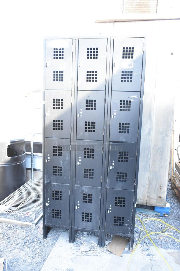 Black metal 12 cubby locker with vented doors, showing moderate wear, suitable for industrial or garage use.