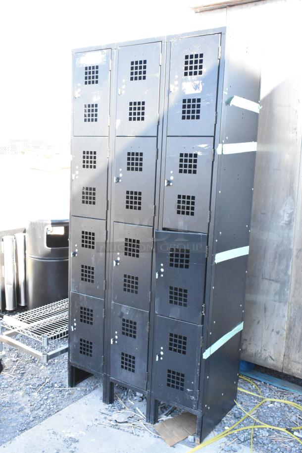 Black metal 12 cubby locker, used condition, features ventilation grilles on doors, minor surface wear visible.