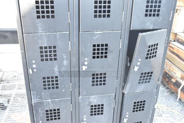 Black metal 12 cubby locker with grid pattern vents. Exhibits signs of wear. Some doors ajar, secured with latches.