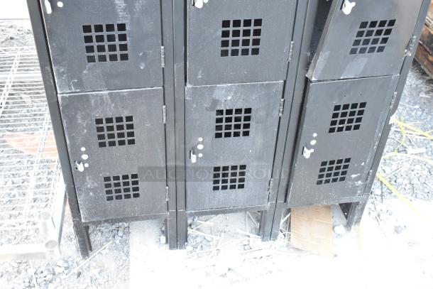Black metal 12 cubby locker with vented doors, used condition, some wear and scratches visible, sturdy design.