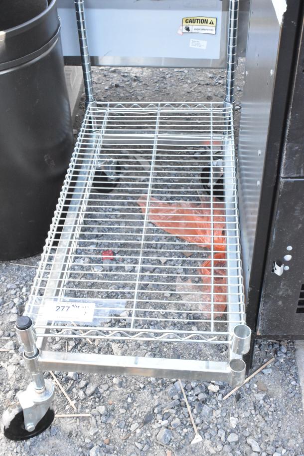 Chrome finish dunnage rack on commercial casters, missing one caster. Caution label visible. Used condition.