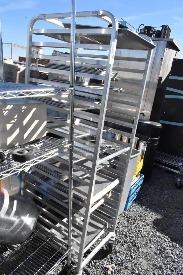 Metal commercial pan transport rack on casters, multiple shelves, sturdy condition, suitable for kitchen use.