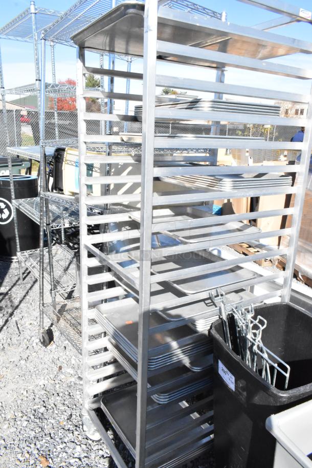 Metal commercial pan transport rack on wheels, holds multiple pans, sturdy construction, some wear, ideal for bakery use.