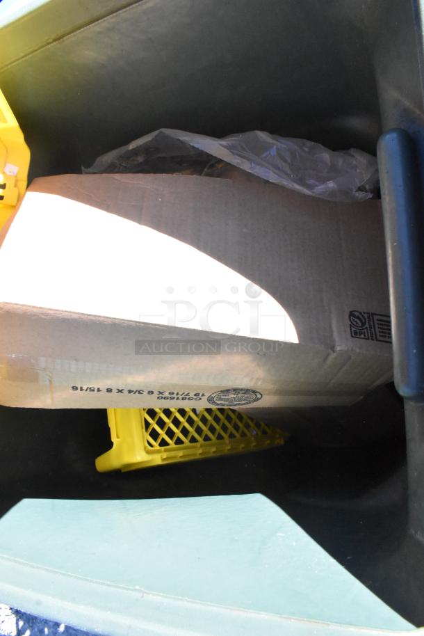 Green trash can with assorted contents including cardboard and plastic, marked with recycling labels. Auction item.