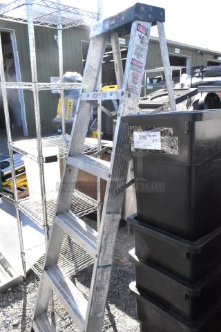 Gorilla Ladders A Frame Ladder, aluminum, visible wear. Tags indicate weight capacity and safety instructions.