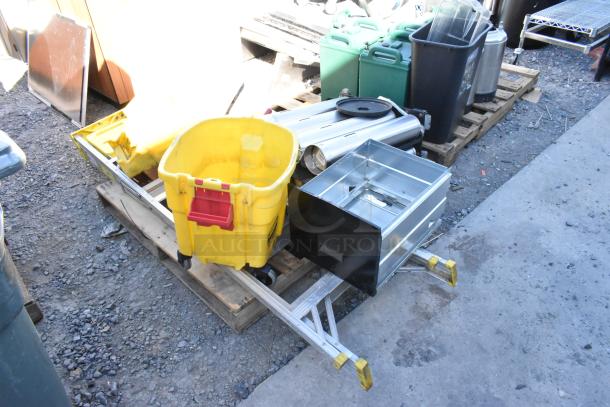 Pallet lot with metal trash can, beverage holder dispensers, wet floor signs, and a yellow bucket. Used condition.