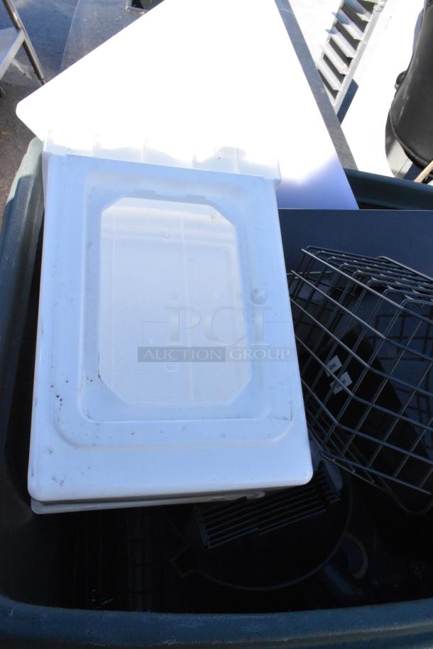 Green poly trash can with contents, featuring a white lid and metal basket. Used condition. Ideal for storage or waste.