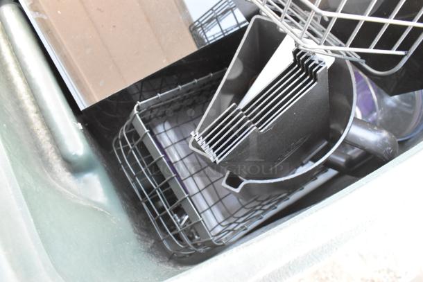 Green poly trash can filled with assorted wire baskets and black plastic trays, showing light wear.