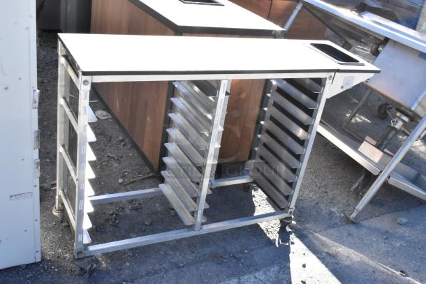 Metal commercial pan transport rack on commercial casters, featuring slots for multiple pans, in used condition.