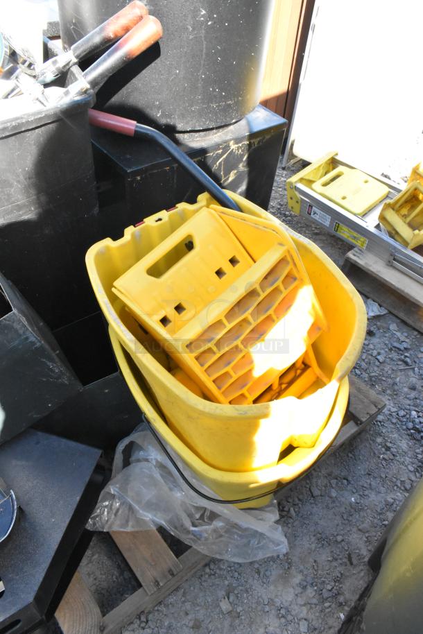 Yellow poly mop bucket with wringer, part of a pallet lot. Includes trash cans, good condition. Shows dirt marks.