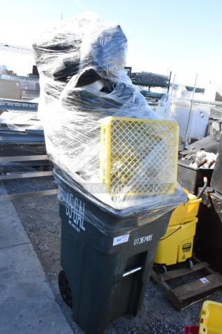 Poly trash can wrapped with plastic, containing miscellaneous items. Marked "65 GAL" and has visible identification tags.