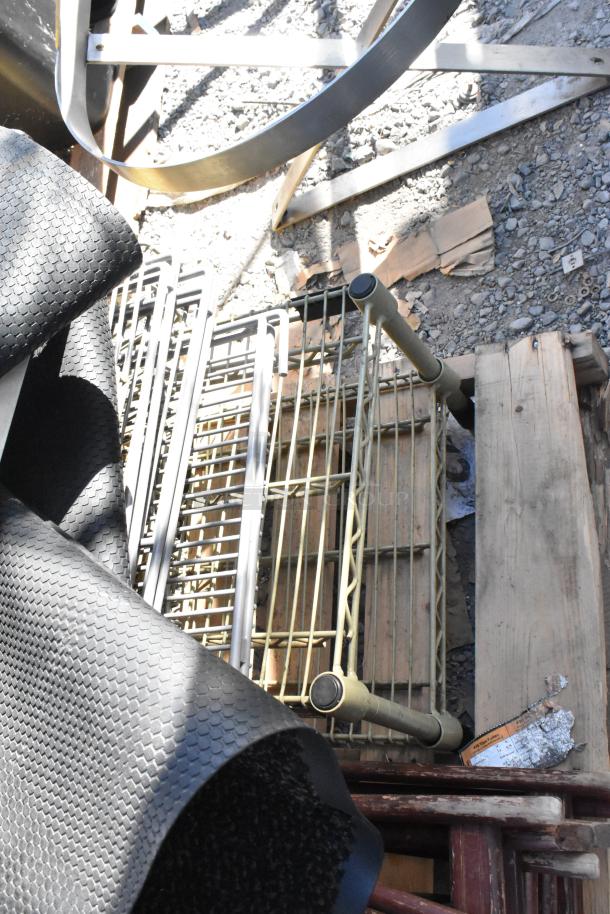Pallet with various items: textured floor mats, metal stool, serving tray stands. Items stacked on wooden base.
