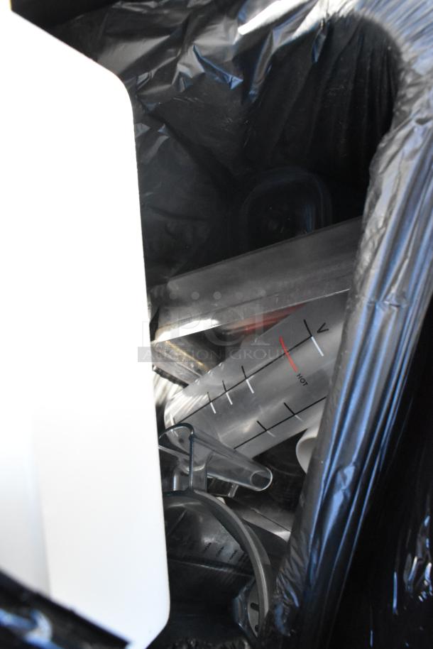 Pallet of miscellaneous items including a trash can, bus bin, and measuring container, in used condition.