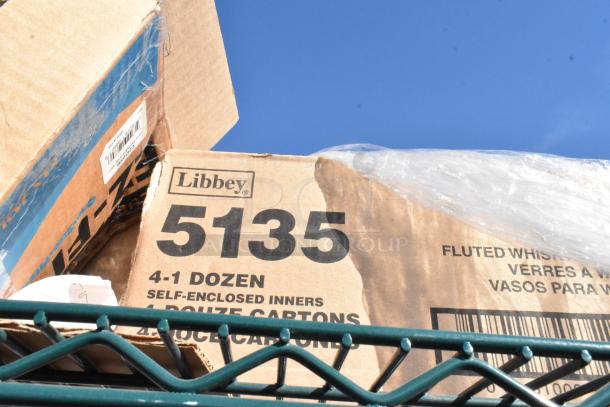 Green 4-tier wire shelving unit with contents including Libbey glass boxes. Includes EZ Fit cup dispensers. Buyer must dismantle.