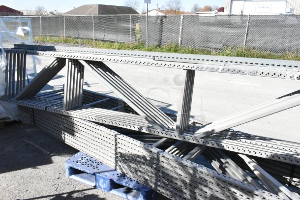 Gray metal pallet racking pieces, size 25x3x144.5, stacked outdoors, ideal for warehouse storage. Good condition.