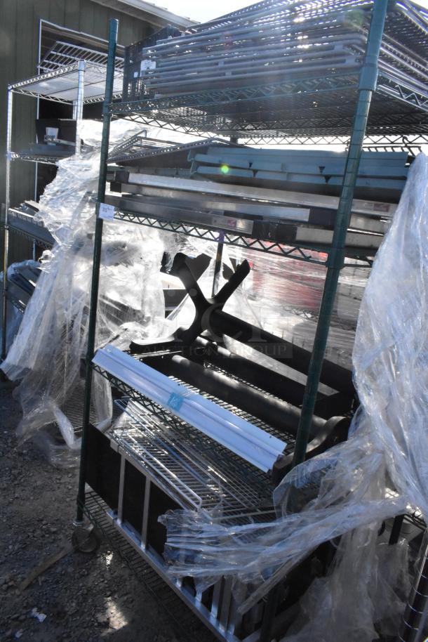 Green finish 4-tier wire shelving unit with metal shelves and various contents, plastic-wrapped, on wheels. Buyer must dismantle.