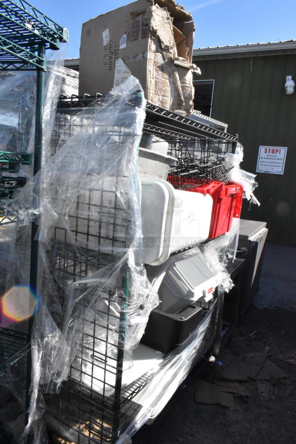Black and green 4-tier wire shelving unit on commercial casters with assorted contents, wrapped in plastic. Buyer must dismantle.