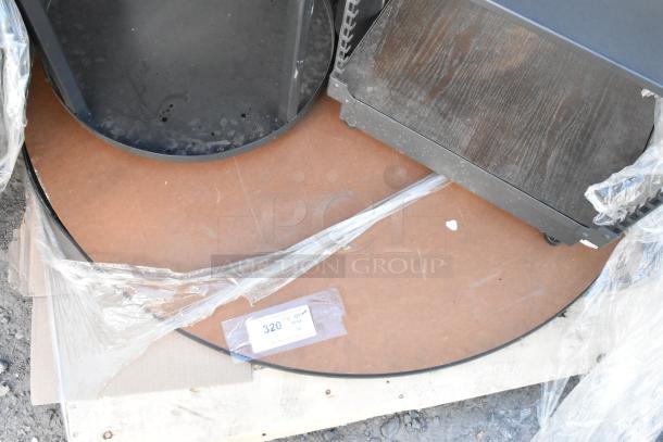 Pallet lot with black cart, round tabletop, wrapped in plastic. Tag shows auction lot number 320. Items appear used.