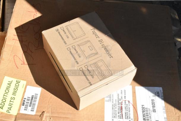 Cardboard box labeled "Paper Dispenser" on a shipping box with labels. Contains note "Additional Parts Inside."