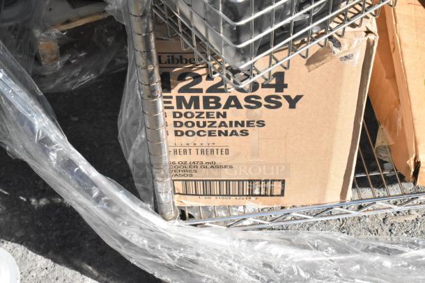 Chrome finish 4-tier wire shelving unit with cardboard box labeled "Libbey Embassy" containing glasses. Buyer must dismantle.