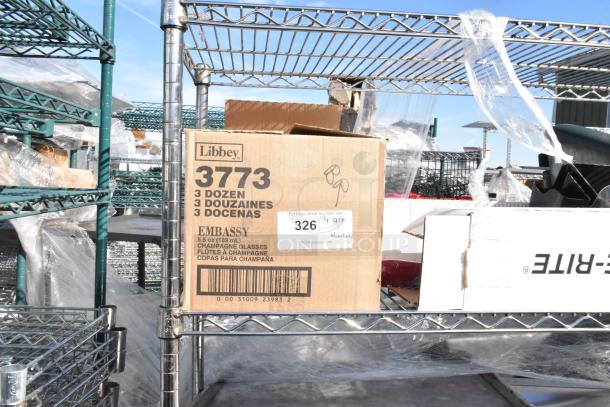 Chrome 4-tier wire shelving unit with Libbey 3773 box of 36 Embassy 5.5 oz champagne glasses. Buyer must dismantle.