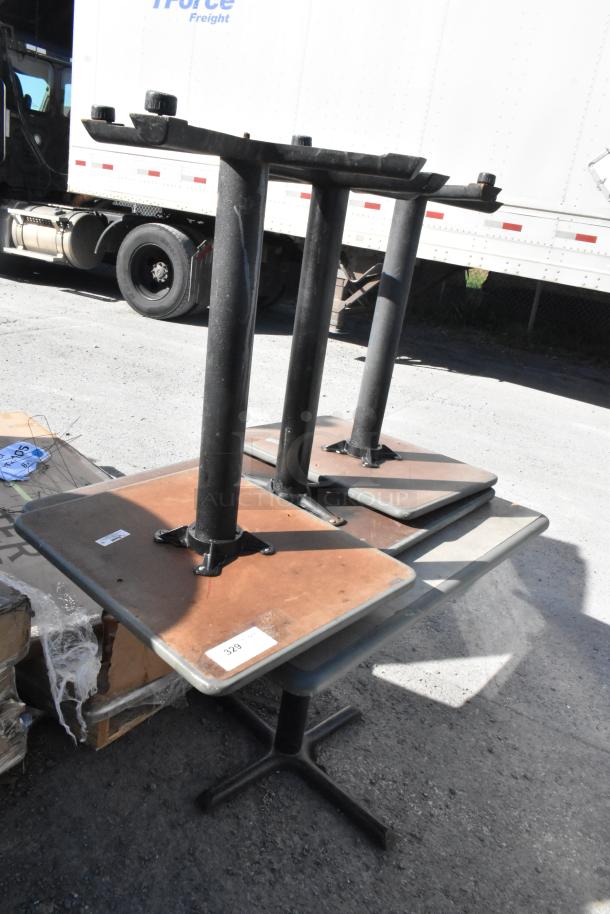 Four various tables with sturdy black metal bases, wooden tops. Condition appears used. Tag visible with lot number 329.