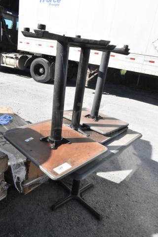 Four various tables with sturdy black metal bases, wooden tops. Condition appears used. Tag visible with lot number 329.