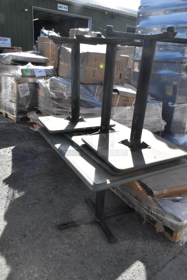 Four metal tables with sturdy bases stacked on a larger table. Auction setting, good condition. Industrial style.