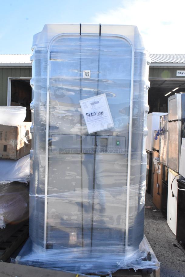 Brand new gray port-a-potty wrapped in plastic, showing minor scratches and dents. Shipping label attached.