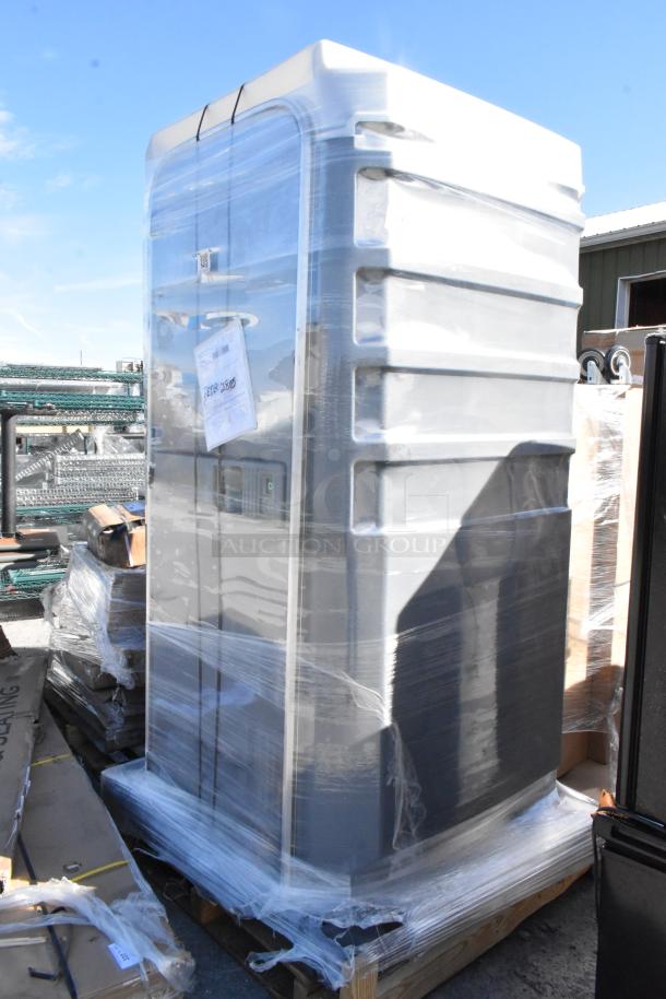 Gray portable toilet, shrink-wrapped on a pallet, labeled "BRAND NEW SCRATCH AND DENT," visibly intact with minor packaging wear.
