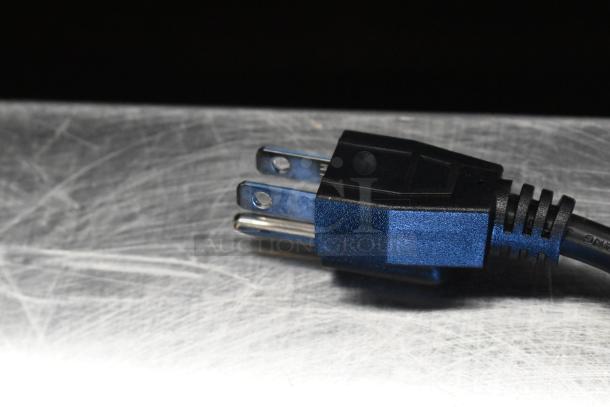 Black power plug of a Hi Tek RWT1661B Soup Kettle Food Warmer, 120 volts, resting on a metal surface.