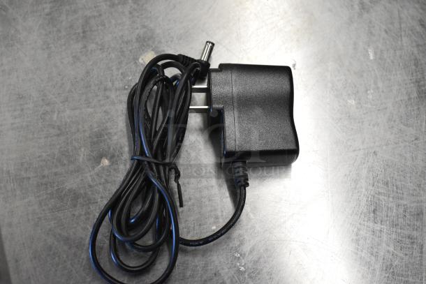 Power adapter for Tor Rey PPC-5/10 scale, black, coiled cable, standard plug, scratches on surface.