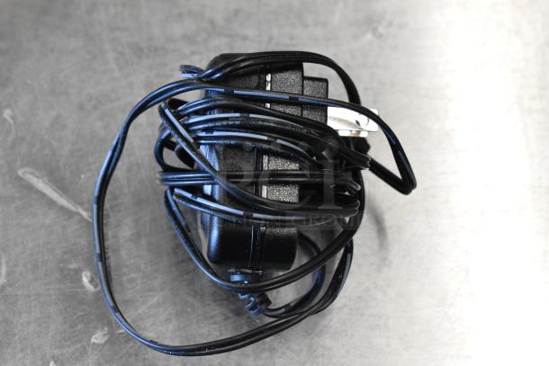 Coiled black power adapter on a metallic surface, associated with auction scales bundle.