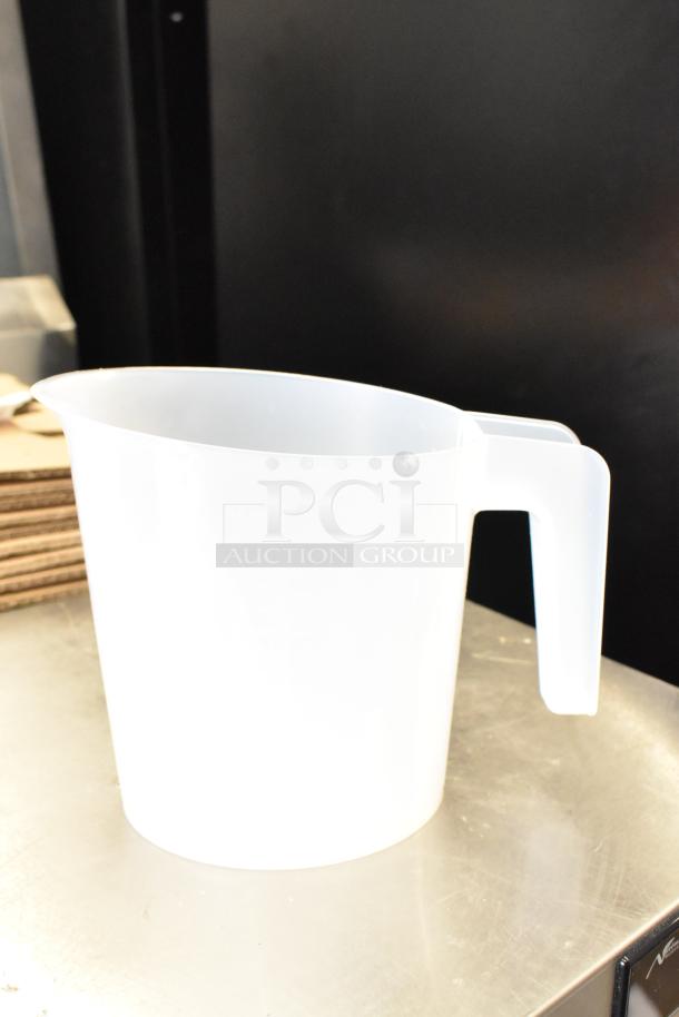 White plastic pitcher on a stainless steel surface, with a curved handle. No visible markings or labels.