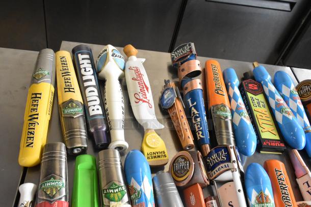 44 various beer tap handles featuring brands like Blue Moon, Oktoberfest, and Surly Brewing Co., in good condition.
